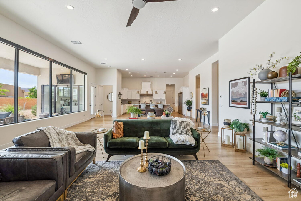 Living room with ceiling fan, light wood-style floors, and recessed lighting