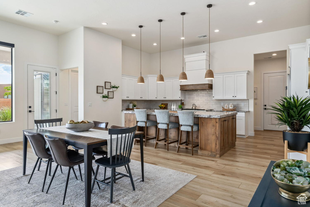 Dining area featuring light wood-style flooring, recessed lighting, and a high ceiling