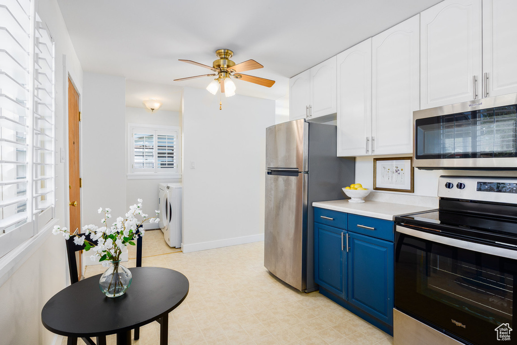 Kitchen featuring appliances with stainless steel finishes, blue cabinets, separate washer and dryer, a ceiling fan, and white cabinets