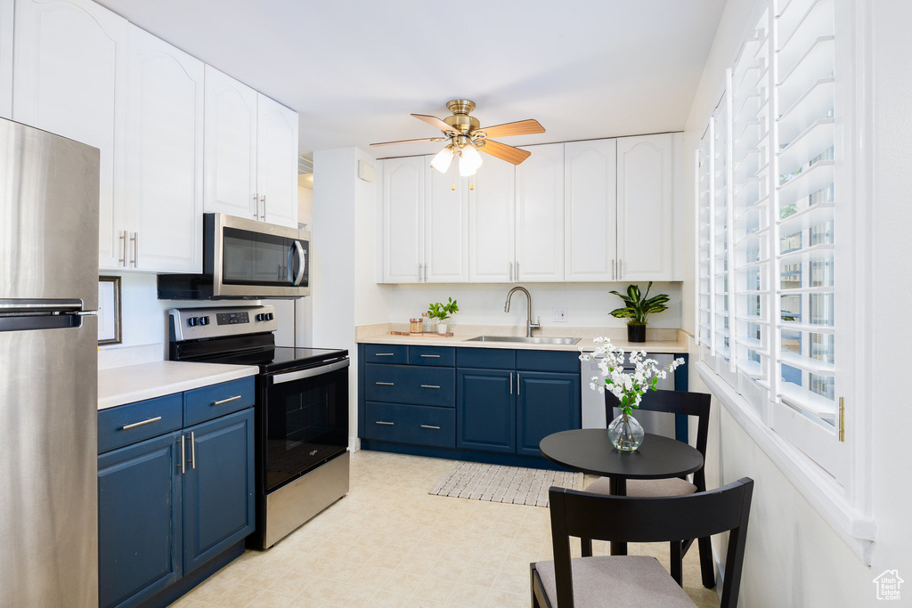 Kitchen featuring appliances with stainless steel finishes, blue cabinetry, light countertops, and white cabinets