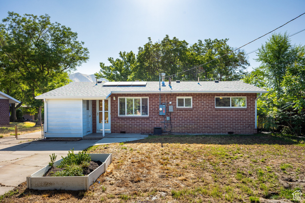 View of front of property featuring solar panels, crawl space, brick siding, and a front lawn