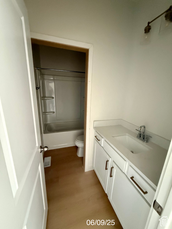 Bathroom featuring vanity, wood finished floors, toilet, and shower / bathtub combination