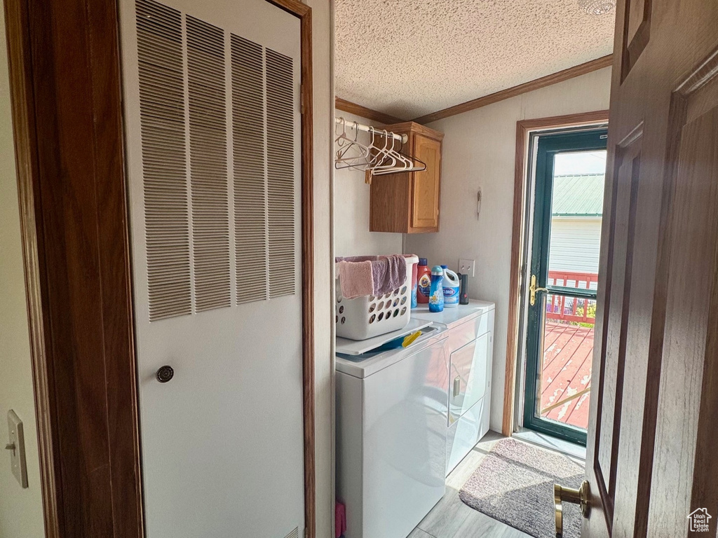 Laundry room featuring a heating unit, independent washer and dryer, cabinet space, light wood-style flooring, and a textured ceiling