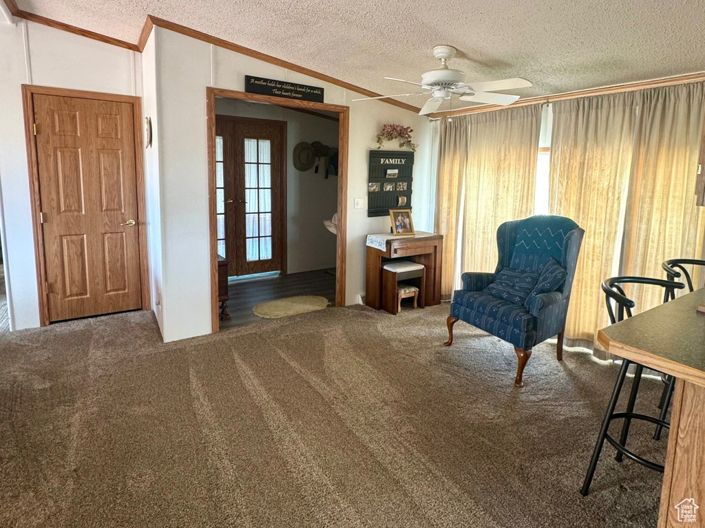Living area featuring crown molding, a textured ceiling, carpet floors, a ceiling fan, and lofted ceiling