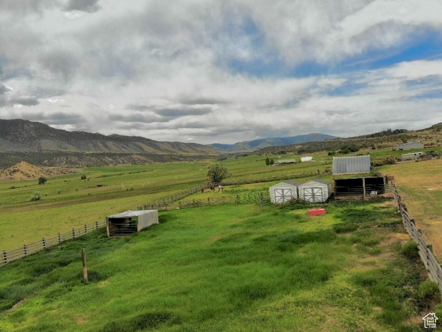 View of yard featuring a rural view, an exterior structure, a mountain view, and a storage unit