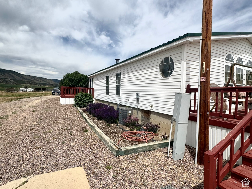 View of side of home featuring a wooden deck and a central air condition unit