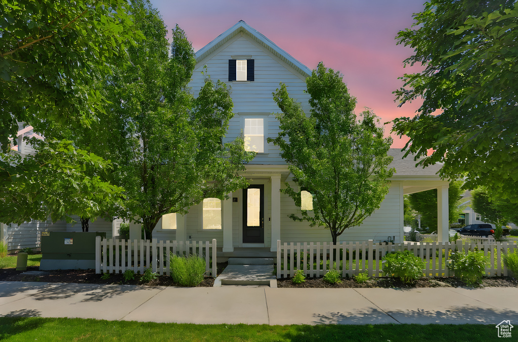 View of property hidden behind natural elements featuring a fenced front yard