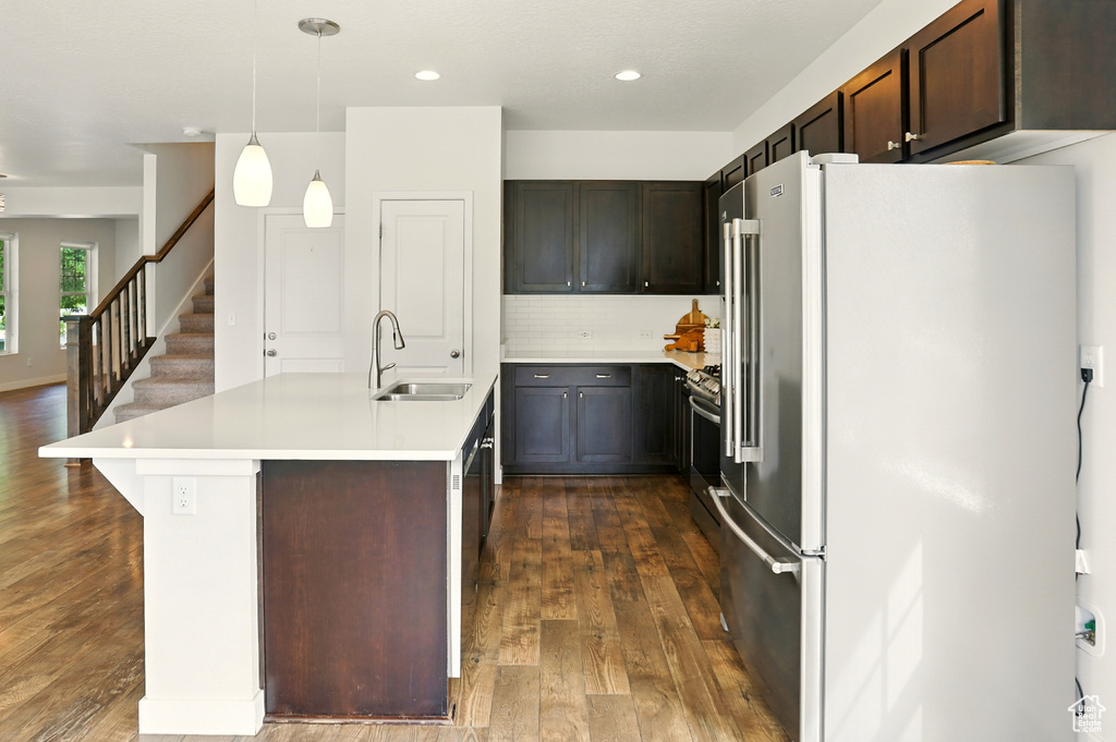 Kitchen with freestanding refrigerator, dark wood finished floors, dark brown cabinets, tasteful backsplash, and light countertops