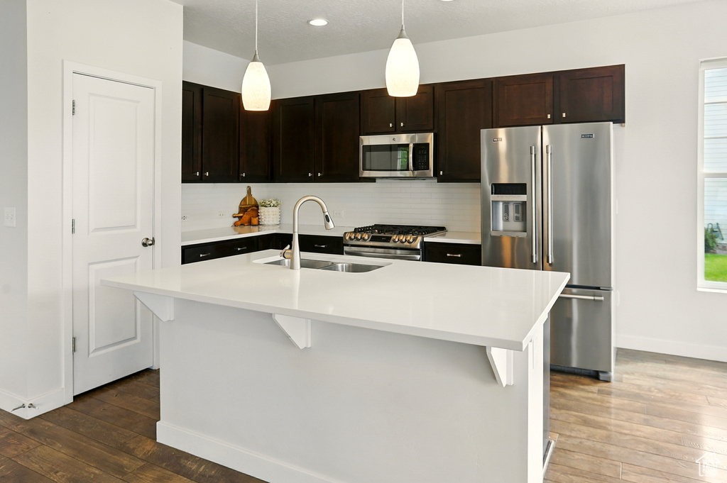Kitchen featuring appliances with stainless steel finishes, hardwood / wood-style floors, light countertops, tasteful backsplash, and recessed lighting