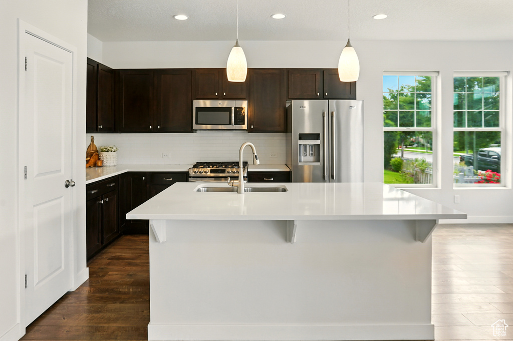 Kitchen featuring stainless steel appliances, dark wood-style floors, light countertops, hanging light fixtures, and recessed lighting