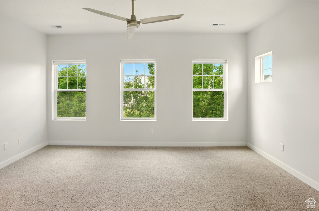 Carpeted empty room featuring a ceiling fan and baseboards
