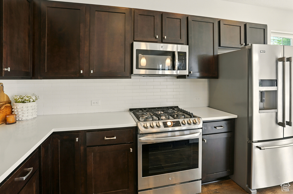 Kitchen featuring appliances with stainless steel finishes, light countertops, and dark brown cabinetry
