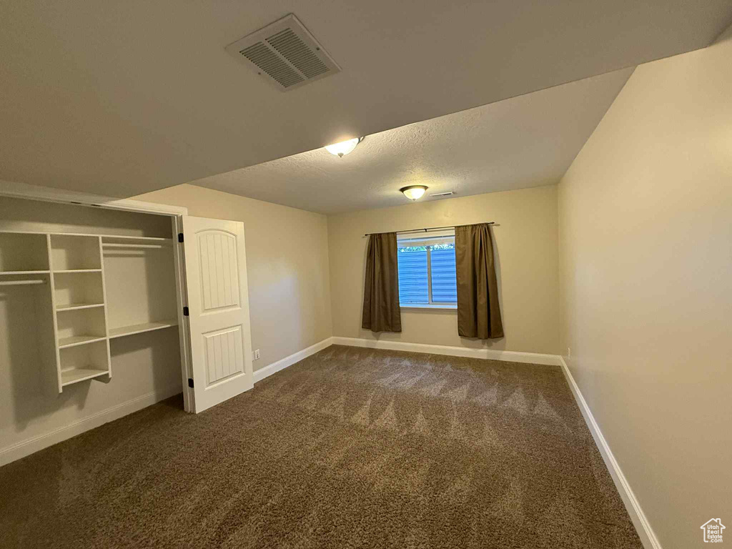 Unfurnished bedroom featuring dark carpet and a textured ceiling