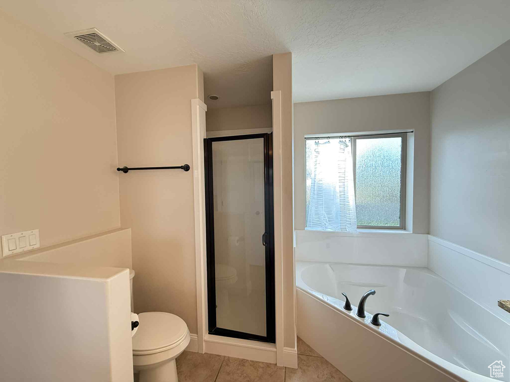 Bathroom with a garden tub, tile patterned flooring, a shower stall, and a textured ceiling
