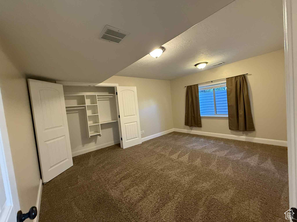 Unfurnished bedroom with dark carpet and a closet
