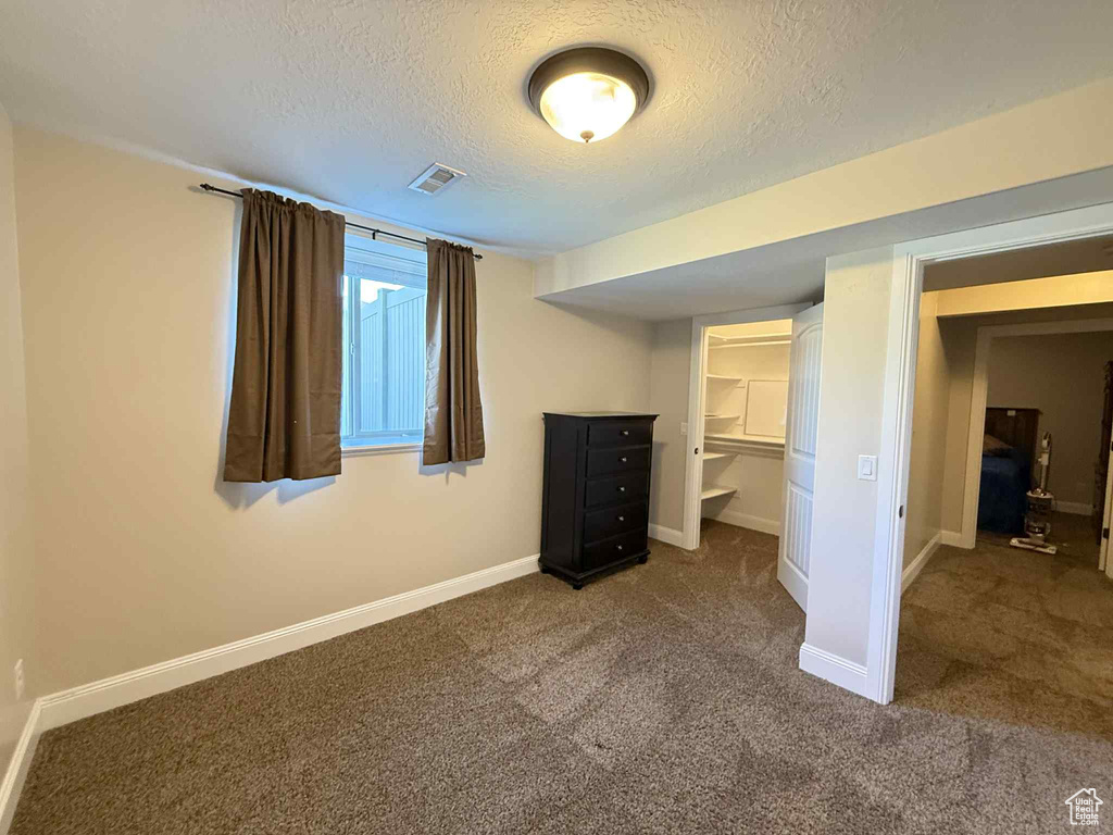 Unfurnished bedroom with a textured ceiling and carpet