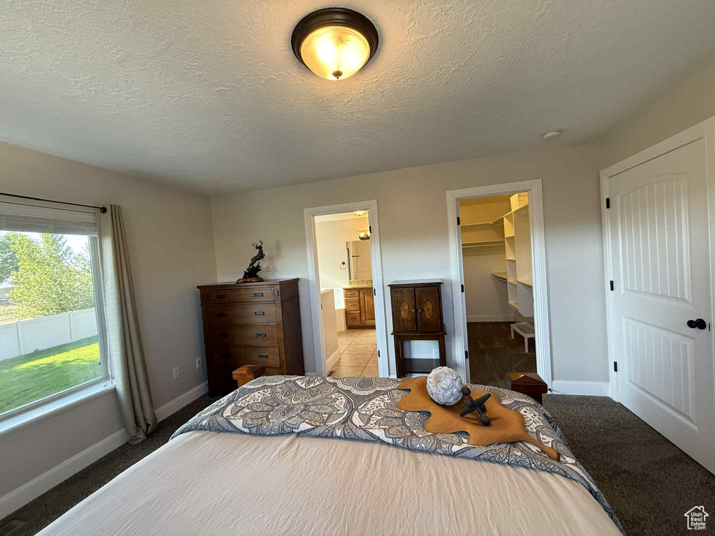 Bedroom featuring a textured ceiling, a walk in closet, ensuite bath, and a closet
