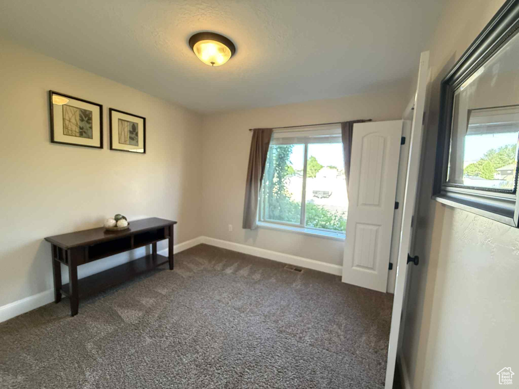 Unfurnished room featuring dark carpet and baseboards