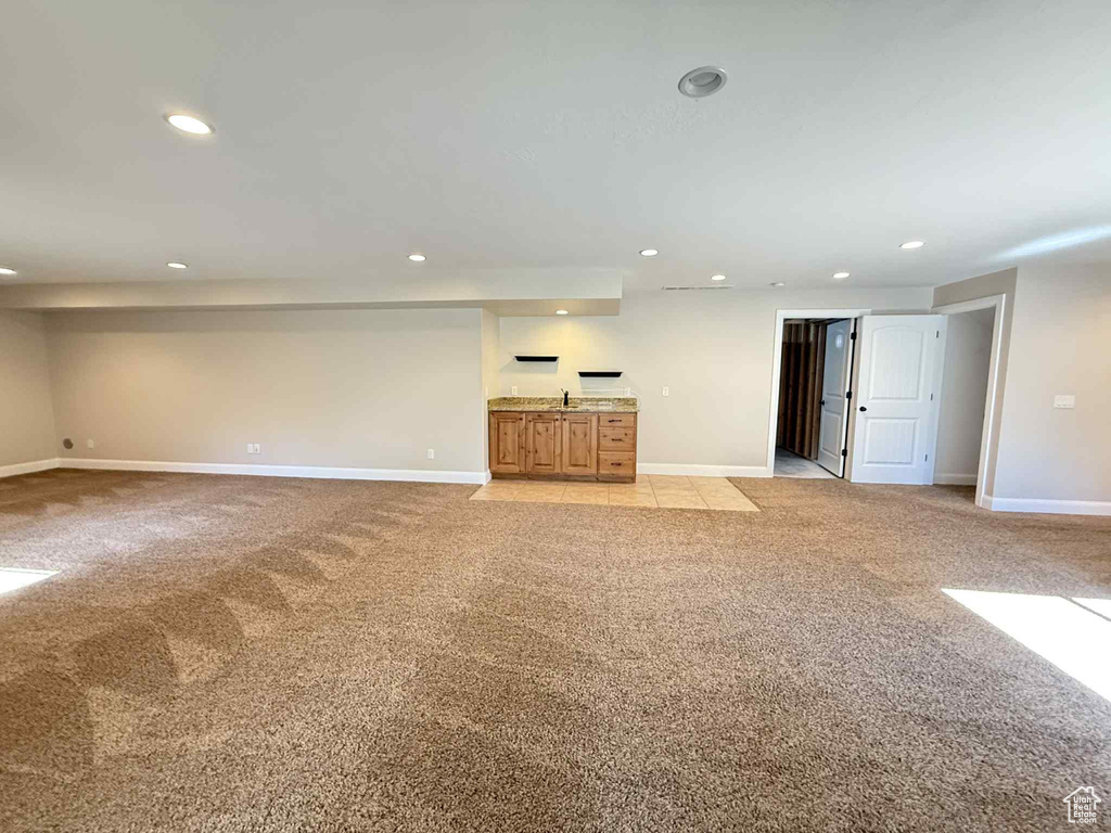 Unfurnished living room with light carpet, recessed lighting, and wet bar
