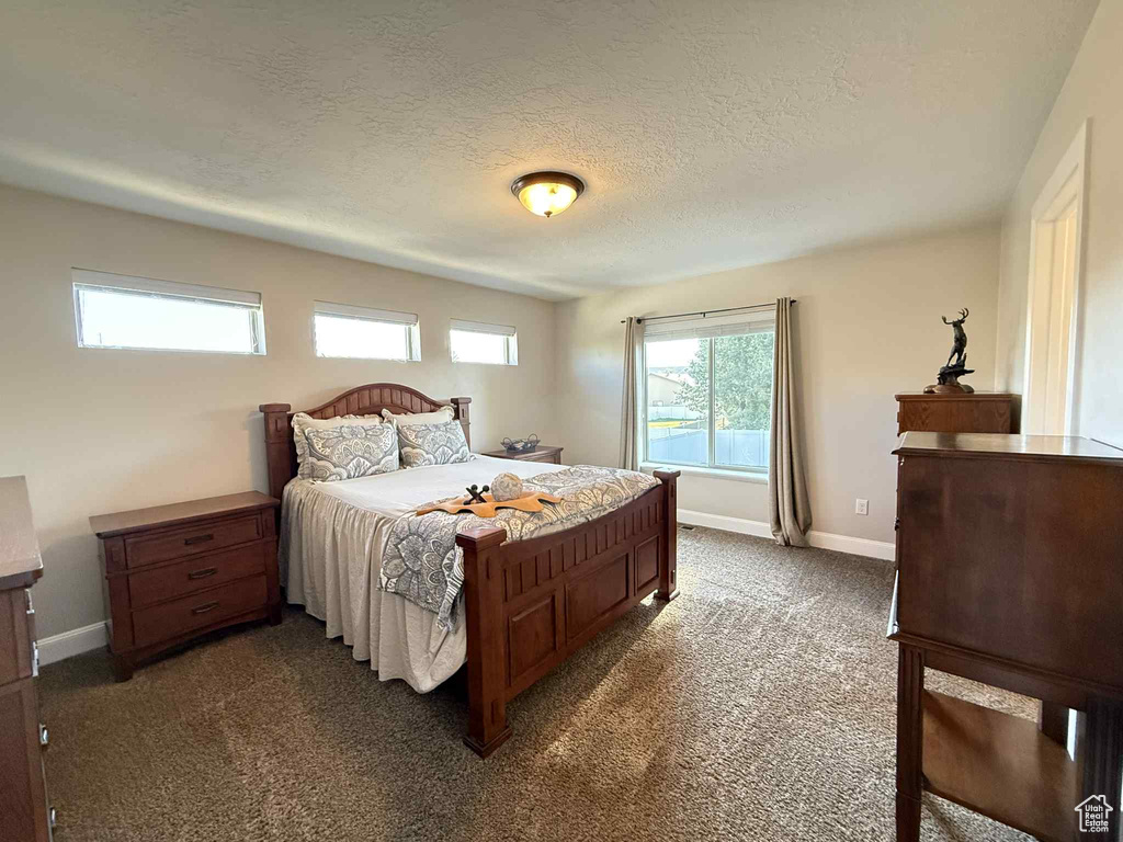 Bedroom featuring dark carpet and a textured ceiling