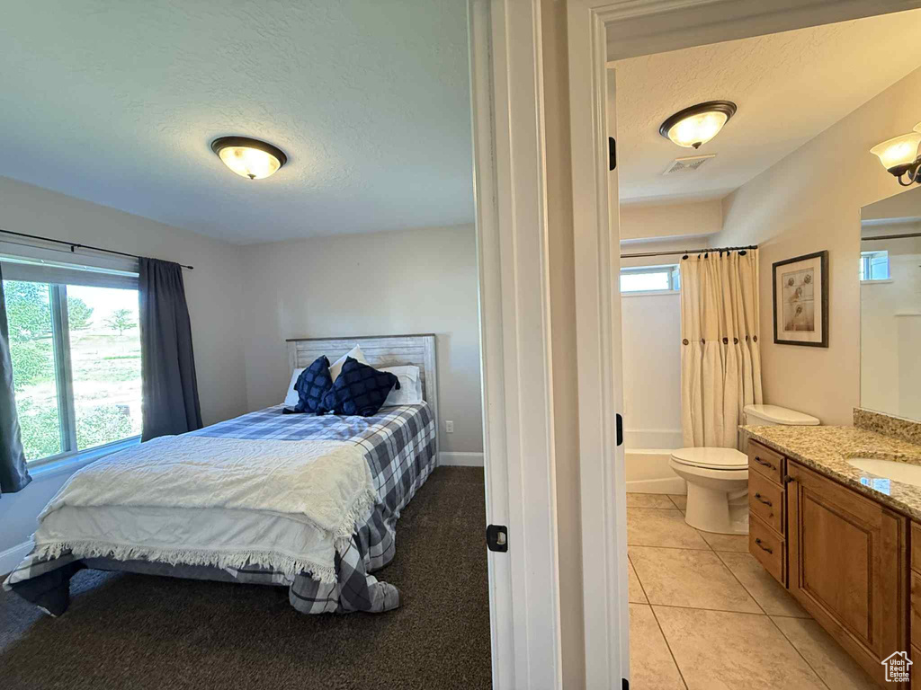 Bedroom featuring a textured ceiling, light tile patterned floors, and ensuite bath