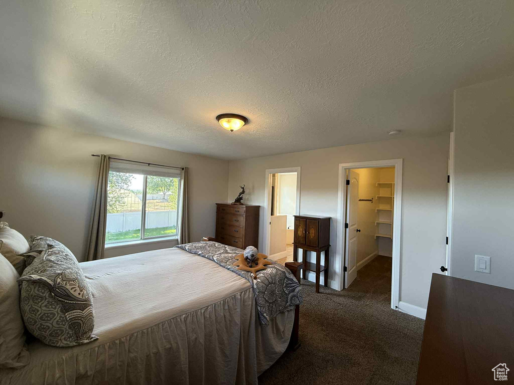 Bedroom with carpet, a textured ceiling, a spacious closet, and ensuite bath