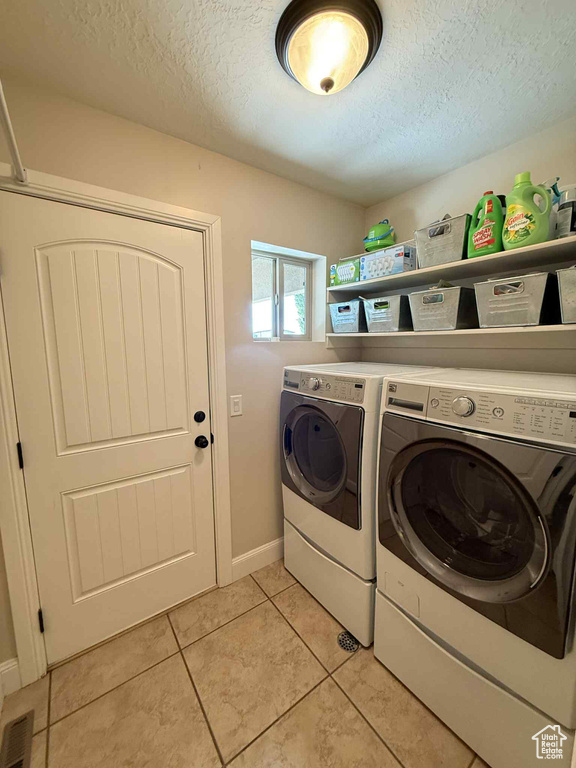 Laundry room featuring independent washer and dryer, a textured ceiling, and light tile patterned floors
