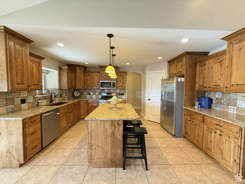 Kitchen with stainless steel appliances, arched walkways, decorative backsplash, a kitchen breakfast bar, and recessed lighting