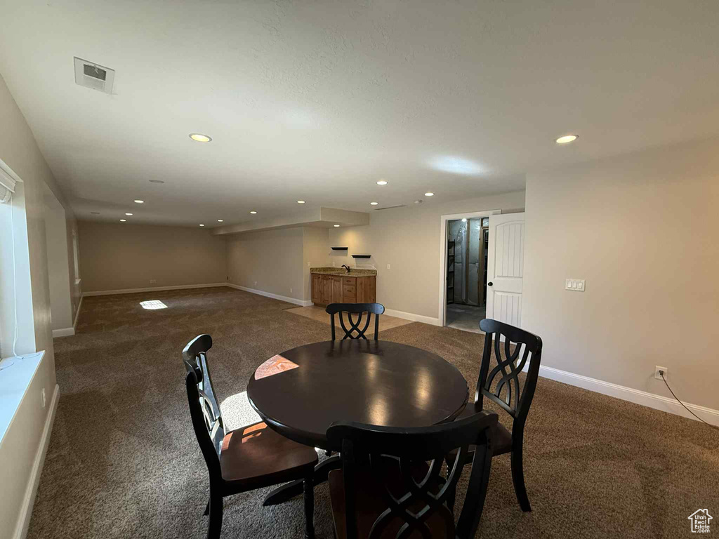 Carpeted dining area with recessed lighting and a bar