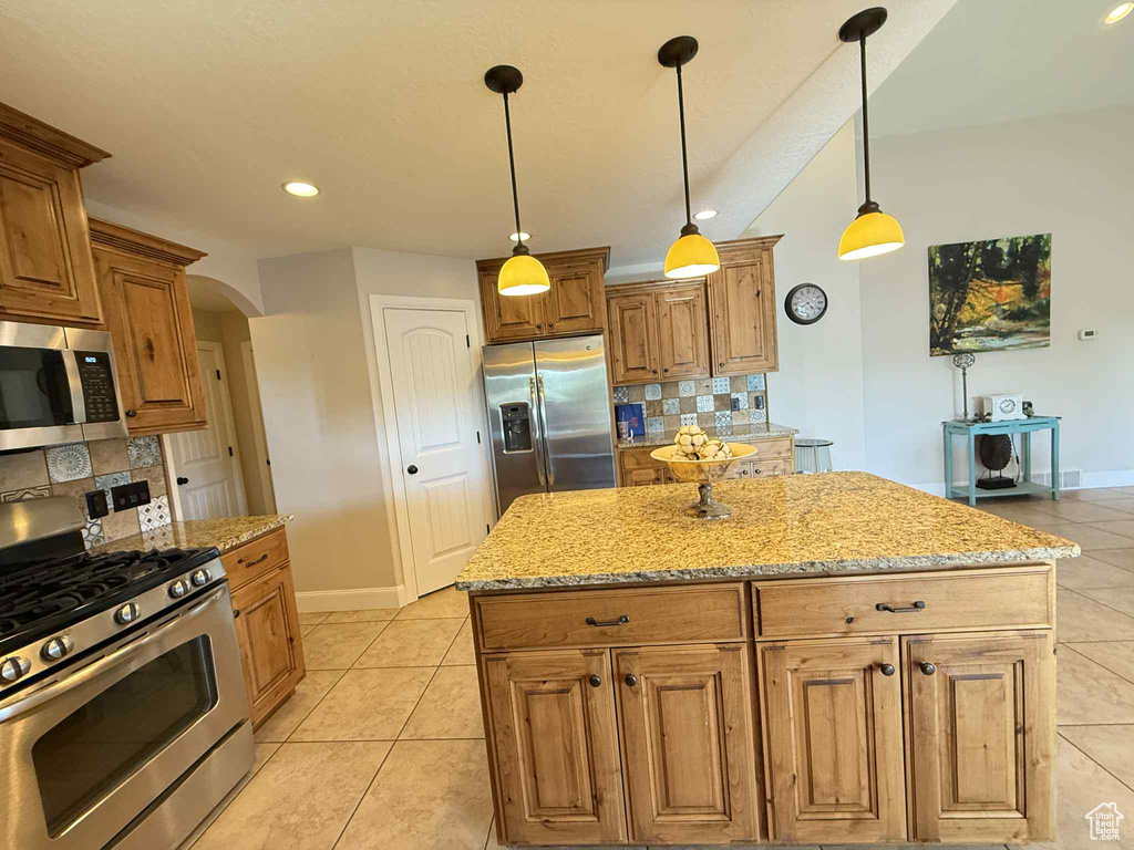 Kitchen featuring stainless steel appliances, arched walkways, decorative backsplash, light tile patterned flooring, and light stone counters