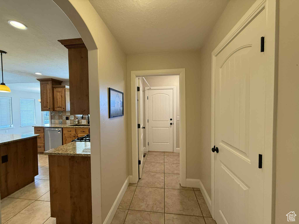 Hall with arched walkways, light tile patterned floors, recessed lighting, and a textured ceiling