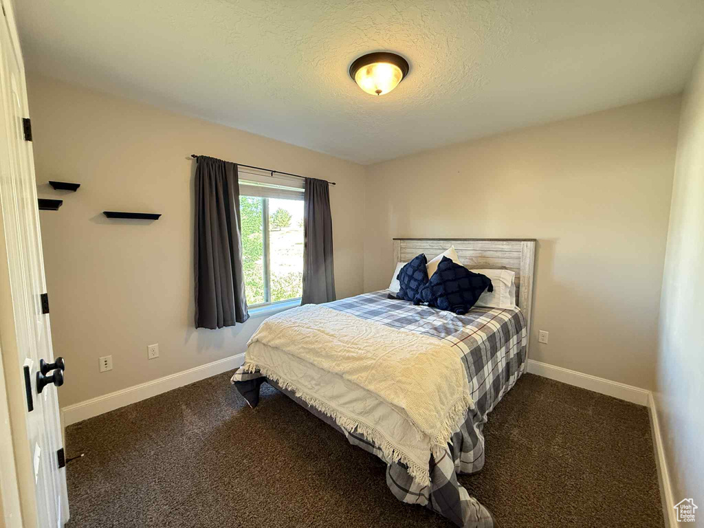 Bedroom with a textured ceiling and dark colored carpet