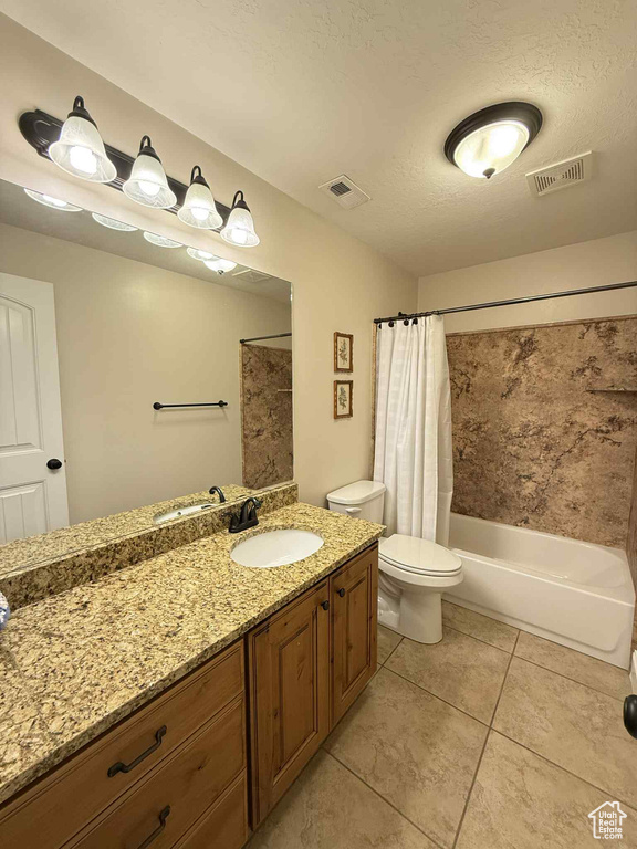 Full bath with vanity, shower / tub combo, tile patterned flooring, and a textured ceiling