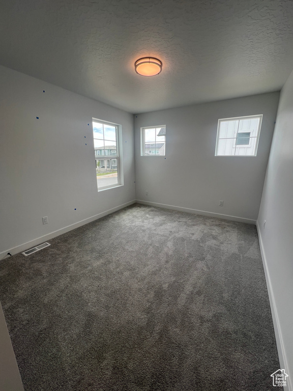 Carpeted spare room with baseboards and a textured ceiling