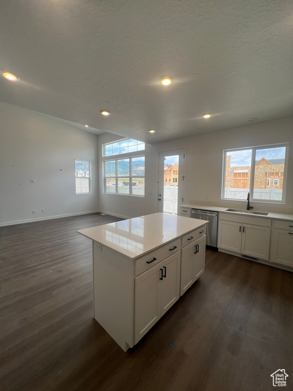 Kitchen with dishwasher, dark wood-style flooring, white cabinetry, a kitchen island, and light countertops
