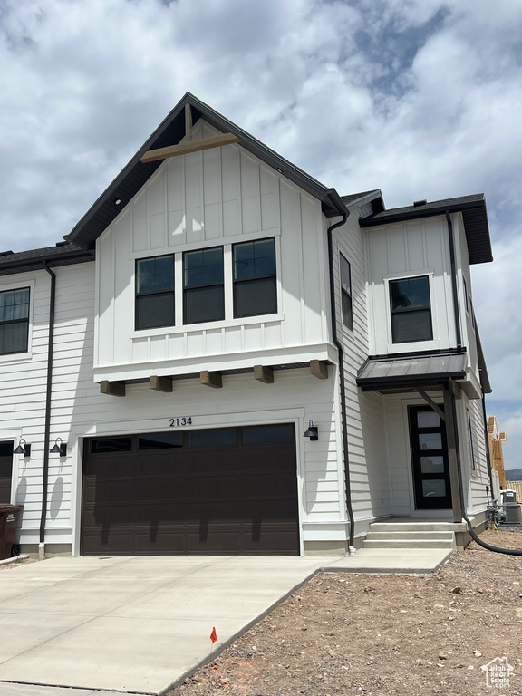 View of front of house with board and batten siding, an attached garage, and concrete driveway