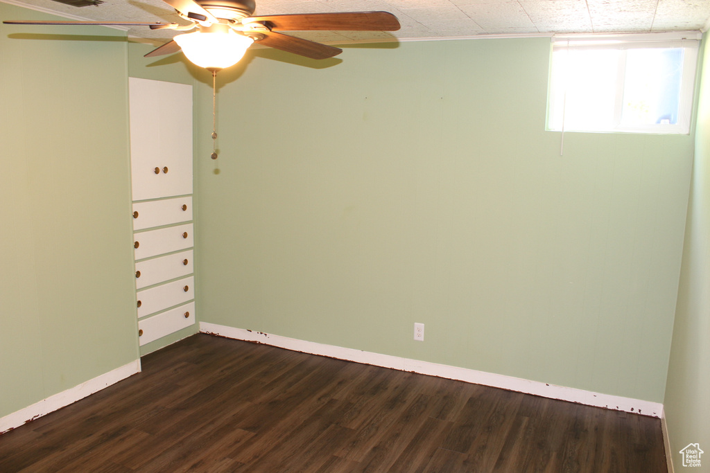 Spare room featuring dark wood-type flooring and ceiling fan
