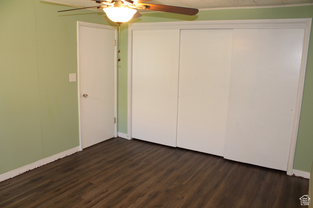Unfurnished bedroom featuring dark wood-style floors, a closet, and a ceiling fan