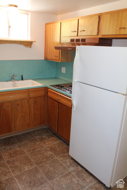 Kitchen with freestanding refrigerator, electric cooktop, and light countertops
