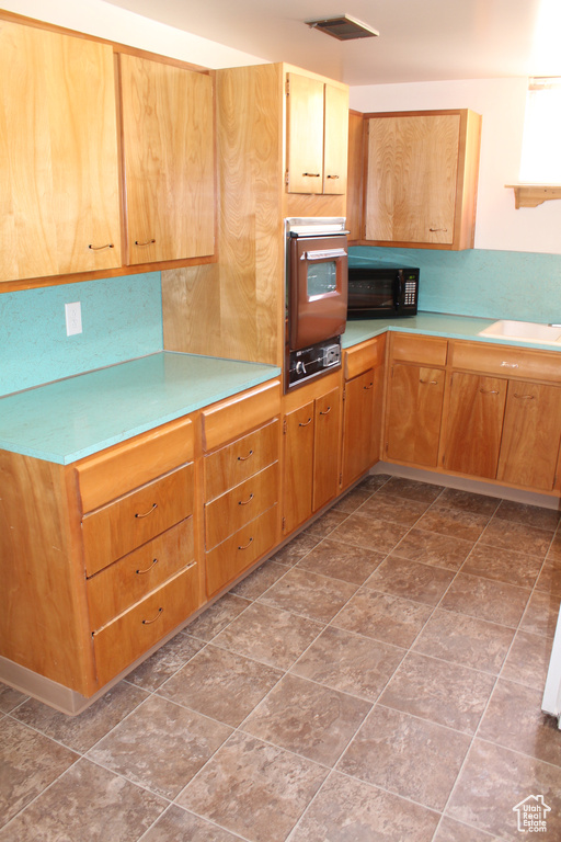 Kitchen with oven, light countertops, and black microwave