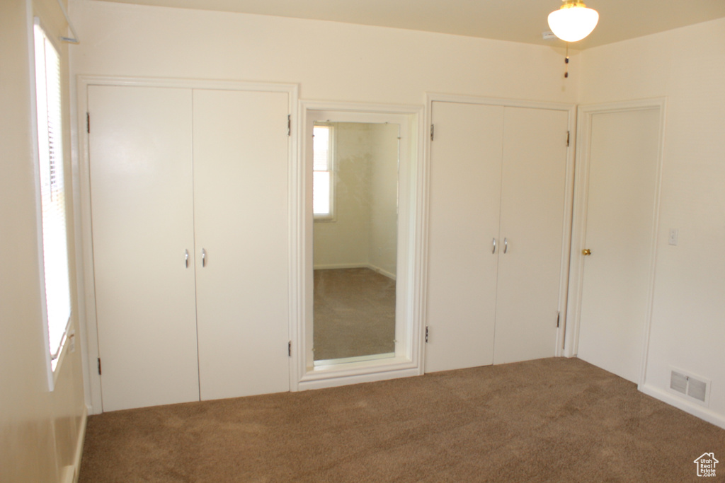 Unfurnished bedroom featuring multiple closets and carpet flooring