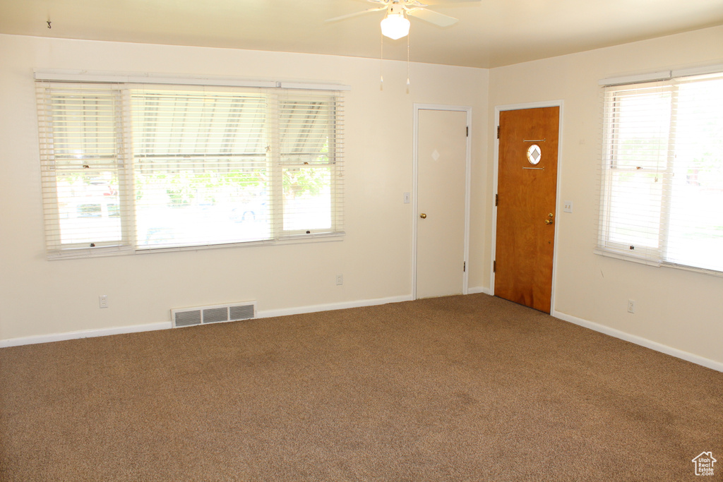 Carpeted spare room with ceiling fan and plenty of natural light