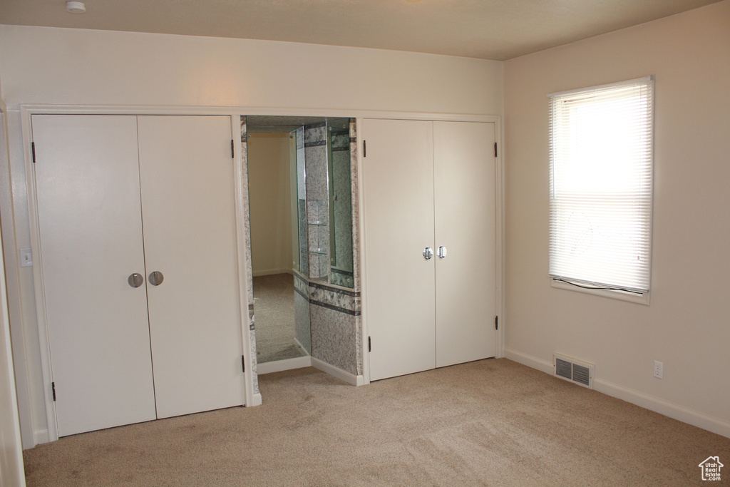 Unfurnished bedroom featuring light colored carpet and baseboards