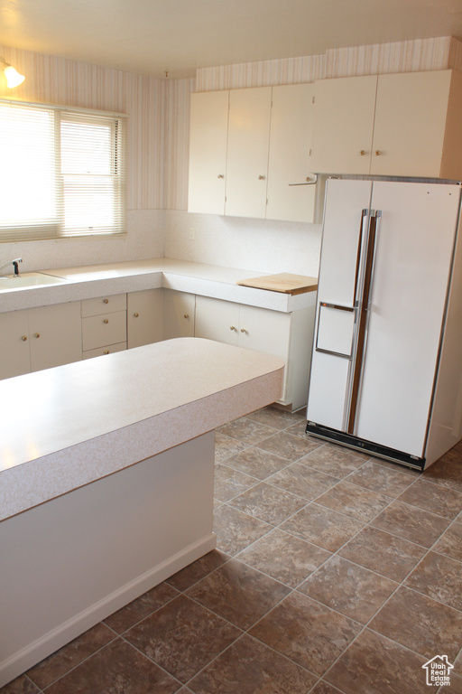 Kitchen featuring freestanding refrigerator, light countertops, and wallpapered walls