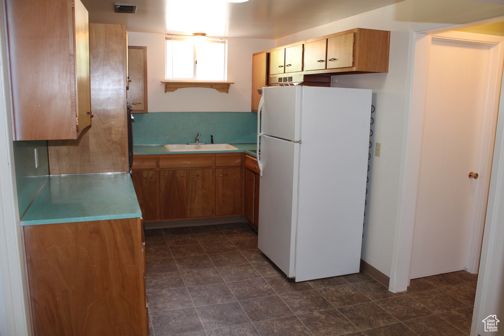 Kitchen with freestanding refrigerator, light countertops, and brown cabinetry