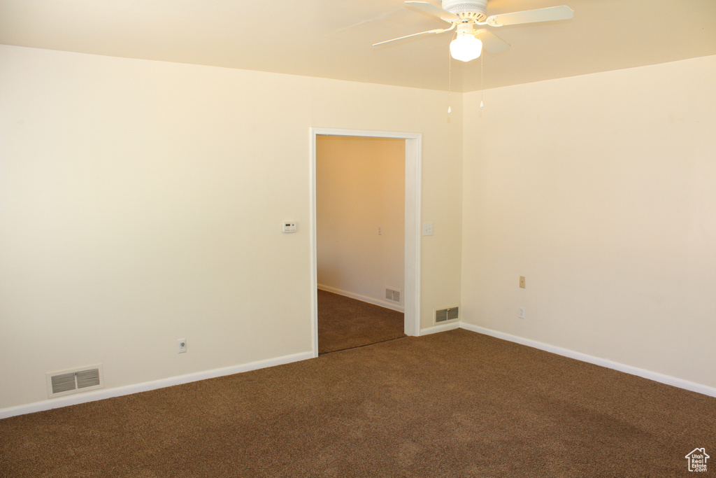 Carpeted empty room with ceiling fan and baseboards