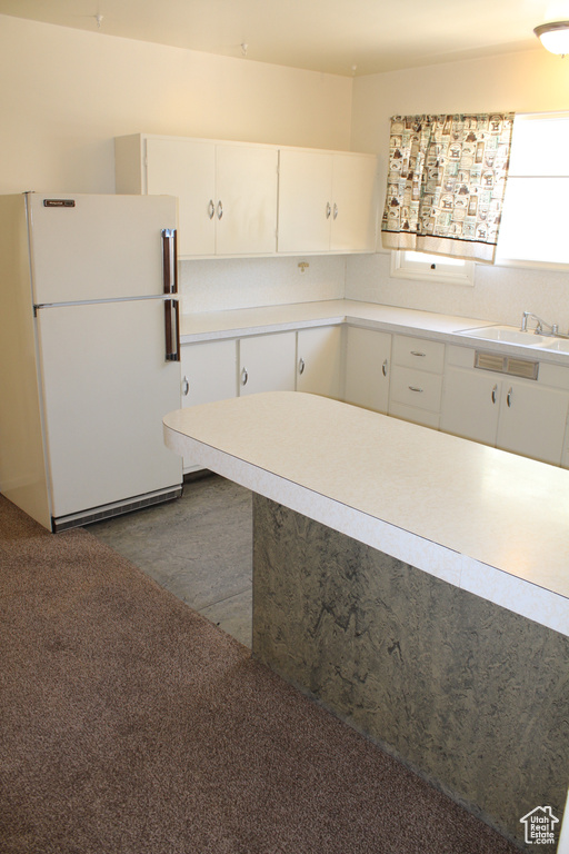 Kitchen featuring freestanding refrigerator, white cabinetry, light countertops, and dark wood-style flooring
