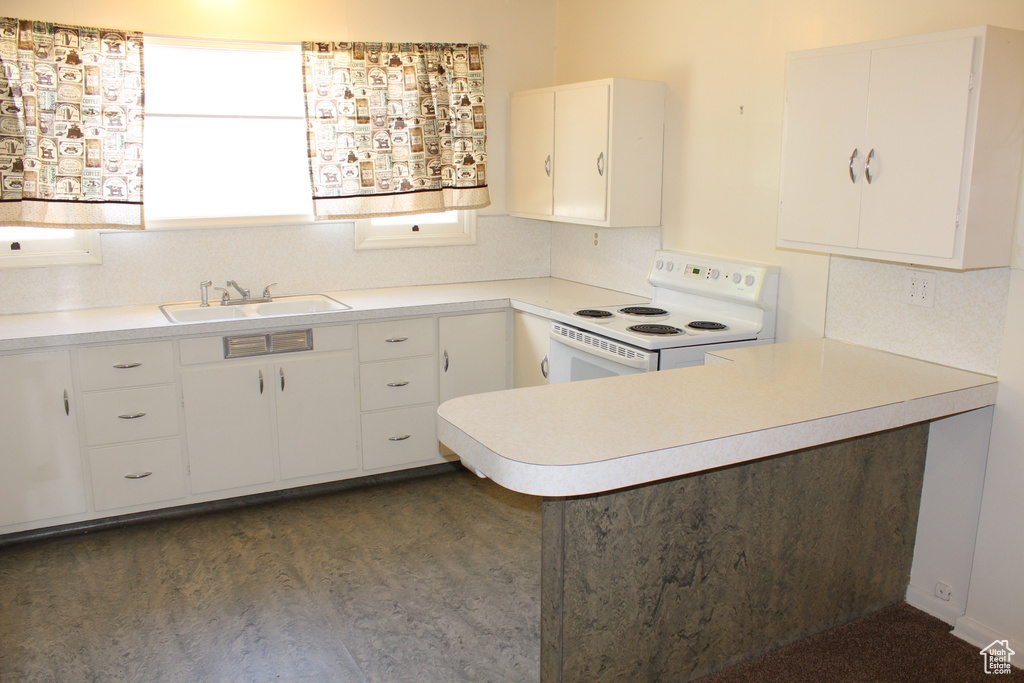Kitchen with white range with electric stovetop, light countertops, white cabinets, and a peninsula