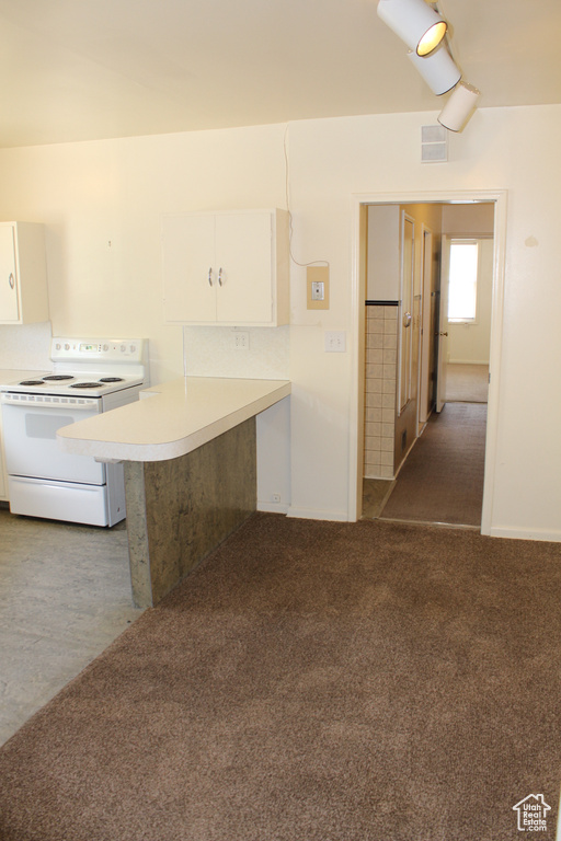 Kitchen with white electric stove, white cabinetry, light countertops, a peninsula, and carpet