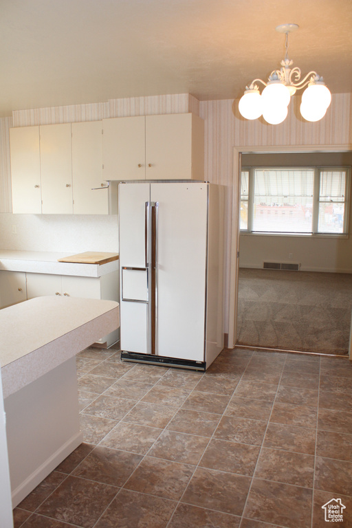 Kitchen with freestanding refrigerator, a chandelier, light countertops, pendant lighting, and cream cabinets